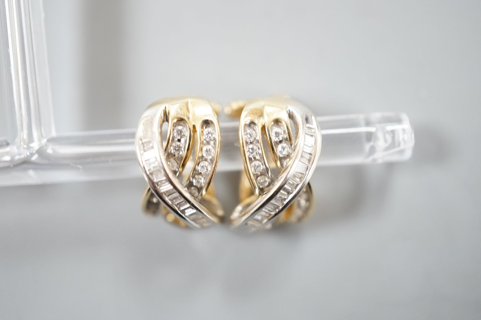 A modern pair of 14k, round and baguette cut diamond set triple row crossover earrings